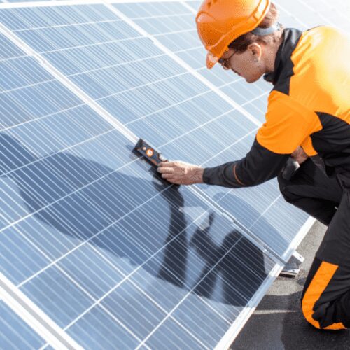 A man in an orange and black suit is working on solar panels.