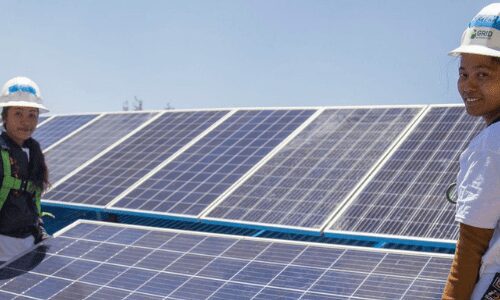 Women installing solar panels on a roof.