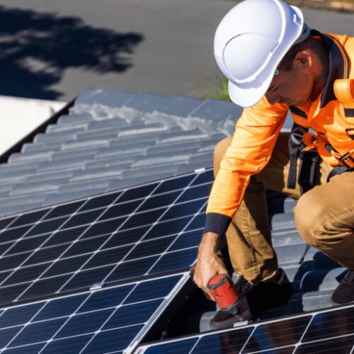 Technician fastening solar panel on metal roof
