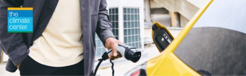 Person charging yellow electric vehicle.