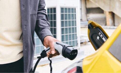 Person charging yellow electric vehicle.