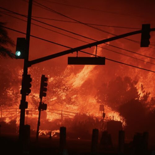 Wildfire raging behind traffic lights at night.