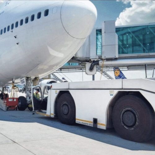 Airplane docked at airport with pushback tug.