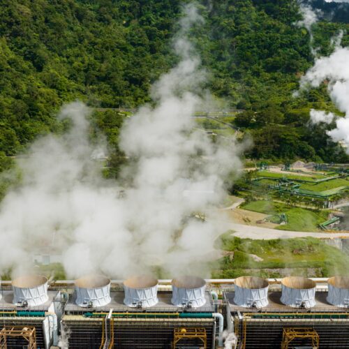 Geothermal power plant surrounded by lush greenery.